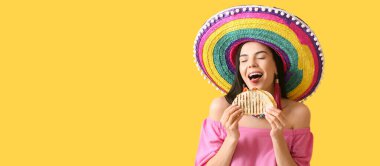 Sombrero 'daki güzel Meksikalı kadın sarı arka planda lezzetli quesadilla yiyor.