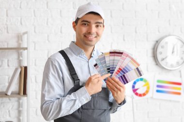 Male painter pointing at color palettes in room