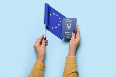 Mavi arka planda Ukrayna pasaportu ve Avrupa Birliği bayrağına sahip kadın