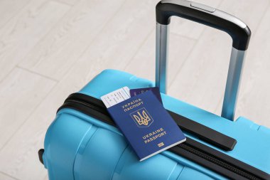 Beyaz ahşap arka planda Ukrayna pasaportlu çanta, yakın plan.