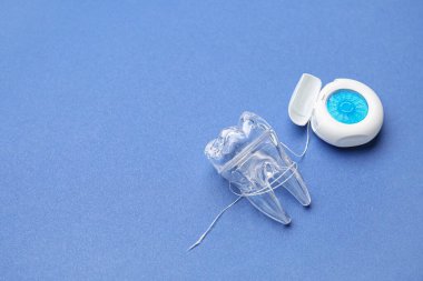 Mavi arka planda diş ipi ve plastik diş modeli olan bir vaka.