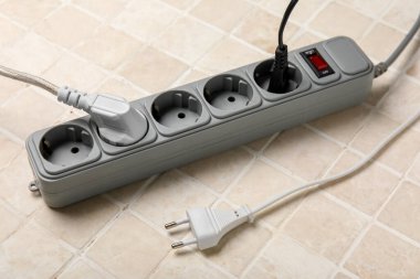 Fayansların arkaplanda olduğu elektrik uzatma kablosu
