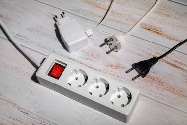 Elektrik uzatma kablosu ve beyaz ahşap zemindeki fişler.