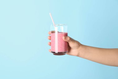 Mavi arka planda pembe smoothie ile kadın eli