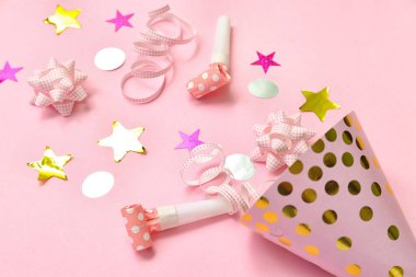 Parti şapkası, düdük ve pembe arka planda konfeti olan kompozisyon