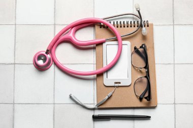 Stetoskop, defter, rozet ve gözlük.