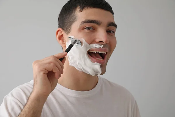 Young Man Shaving Light Background — Stock Photo, Image