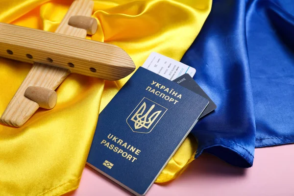 stock image Passport with toy airplane and flag of Ukraine on pink background, closeup