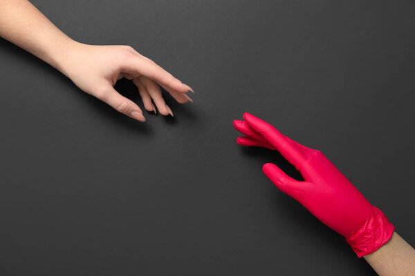 Woman and wooden hand in rubber glove on black background
