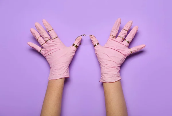 Woman in pink gloves with rings on lilac background
