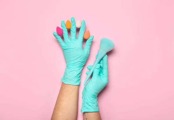 スポンジやブラシでゴム手袋でメイクアーティストピンクの背景 — ストック写真