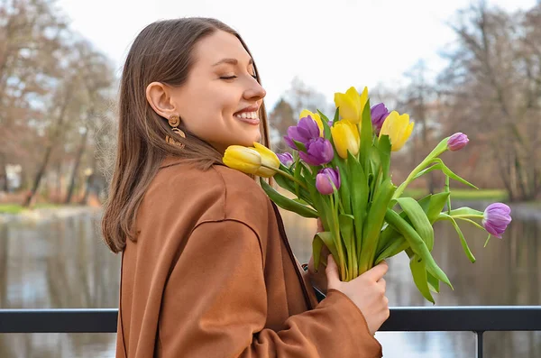 Young woman with tulips on embankment