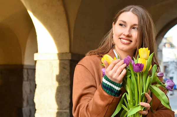 Young woman with tulips on city street, closeup