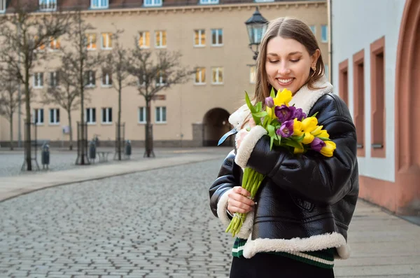 stock image Young woman with tulips on city street