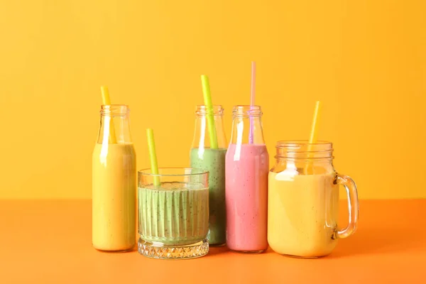 stock image Glasses and bottles of colorful smoothie on color background