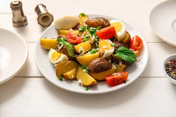 Plate of tasty potato salad with eggs and tomatoes on light background