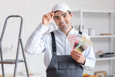 Odasında renk paletleri olan erkek ressam