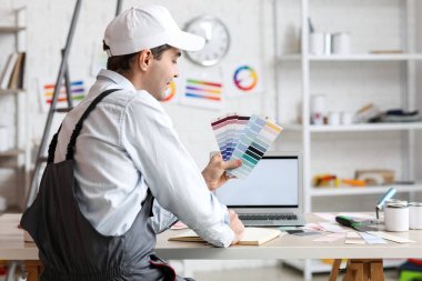 Masada not defterine renk paletleri yazan erkek ressam