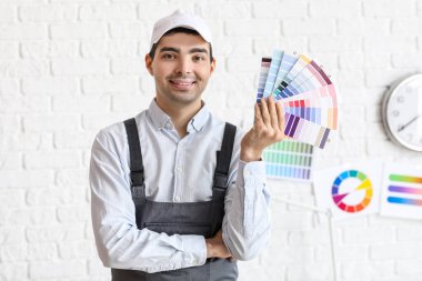 Male painter with color palettes near white brick wall
