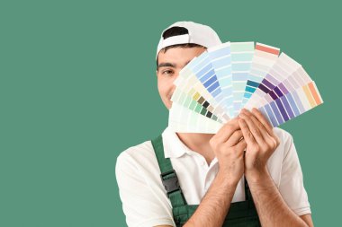 Male painter with color palettes on green background, closeup