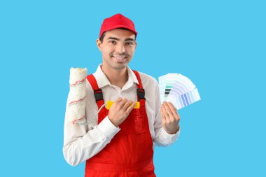 Renk paletleri ve mavi arka planda silindiri olan erkek ressam