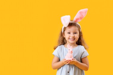 Tavşan kulaklı küçük kız, sarı arka planda Paskalya tavşanı.