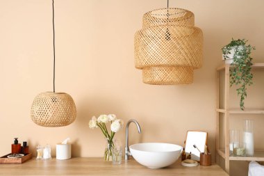 Sink, vase with flowers and bath accessories on table in bathroom