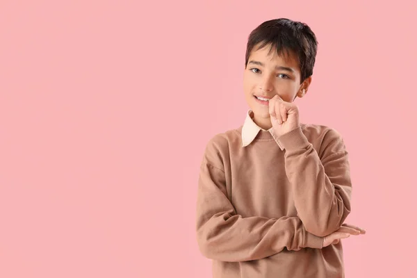 Little boy biting nails on pink background