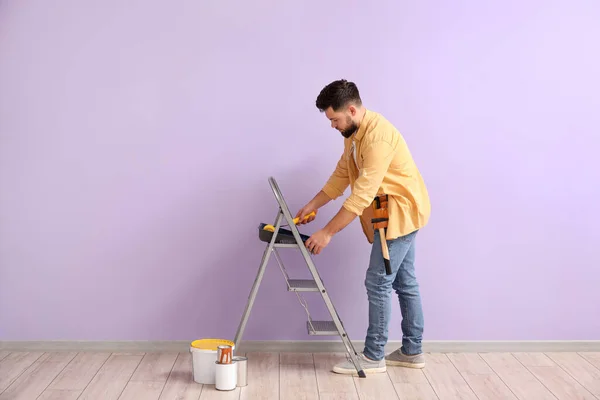 Young Man Paint Roller Ladder Lilac Wall — Stock Fotó
