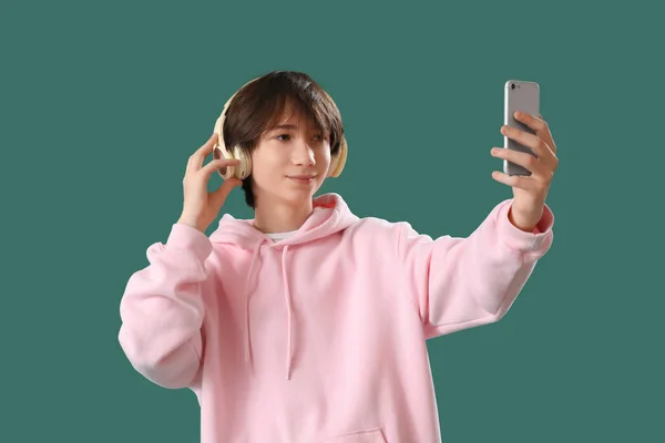 Хлопчик Підліток Навушниках Мобільним Телефоном Бере Селфі Зеленому Фоні — стокове фото