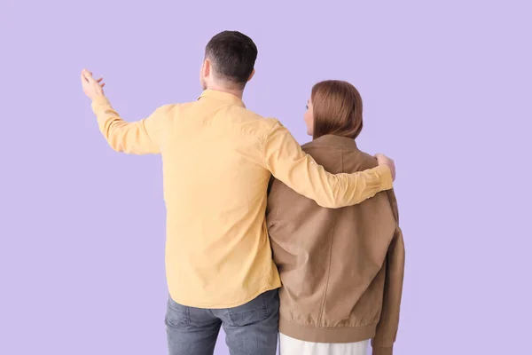 Young Man His Wife Showing Something Lilac Background Back View — Stock Photo, Image