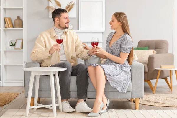 stock image Young couple with glasses of wine sitting on sofa at home