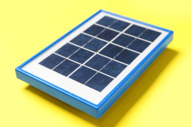 Portable solar panel on yellow background, closeup