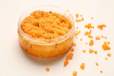 Jar of body scrub and sea salt on light background
