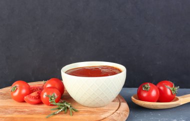 Gri arkaplanda bir kase lezzetli domates ezmesi.