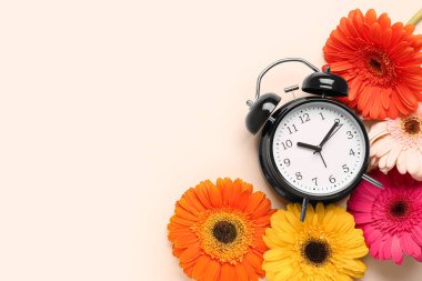 Çalar saat ve bej arka planda güzel Gerbera çiçekleri