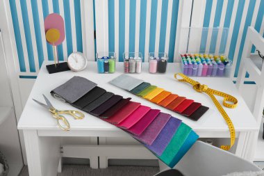 İplik makaraları, kumaş örnekleri, makas ve atölye bandıyla terzinin işyeri