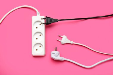 Elektrik uzatma kablosu ve pembe arka plandaki prizler
