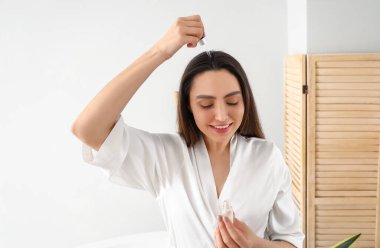 Evde saç dökülmesi tedavisi için serumu olan bir kadın.