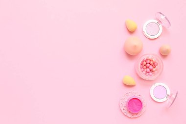 Pembe arka planda makyaj süngeri olan dekoratif kozmetik ürünler.