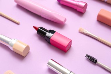 Eflatun arkaplanda makyaj fırçası olan dekoratif kozmetik ürünler.