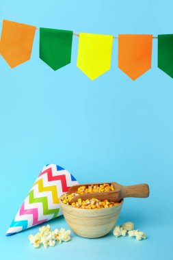 Bir top mısır, parti şapkası ve mavi arka planda bayraklarla dolu bir kase. Festa Junina (Haziran Festivali) kutlaması
