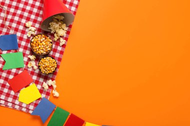 Patlamış mısırlı parti şapkası, kaseler, bayraklar ve kırmızı arka planda peçete. Festa Junina (Haziran Festivali) kutlaması