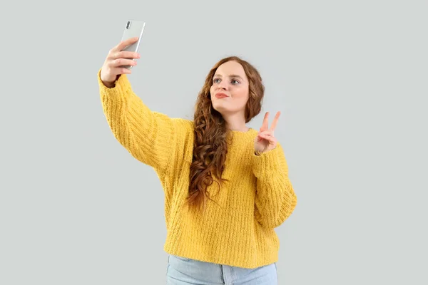 Hermosa Pelirroja Con Teléfono Móvil Tomando Selfie Sobre Fondo Gris — Foto de Stock