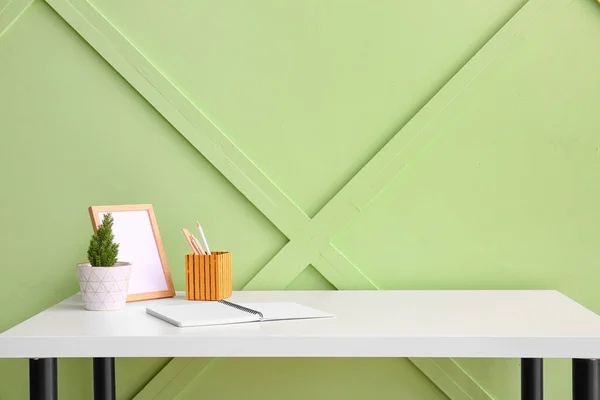 緑の壁の近くの文房具 フレーム 植物のある職場 — ストック写真