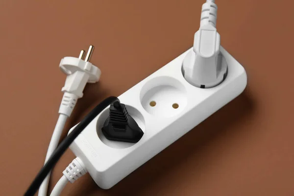 Electric extension cord with plugs on brown background