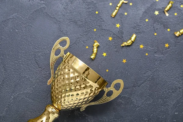 Gold cup with serpentine and stars on dark background, closeup