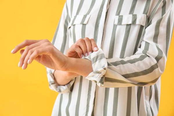 Young woman rolling up her sleeve on yellow  background, closeup