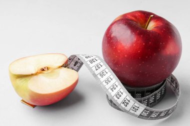 Elma ve gri arkaplanda ölçüm bandı. Diyet kavramı