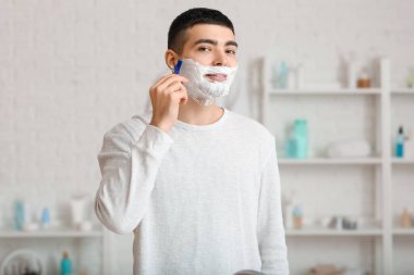 Morning of young man shaving in bathroom